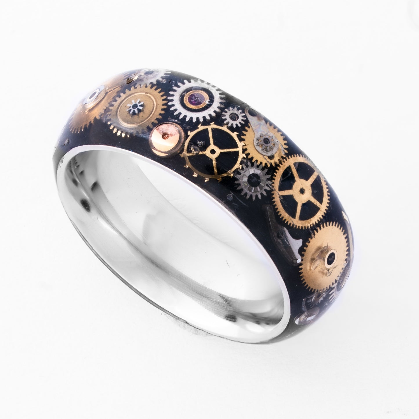 Tungsten ring with gold and silver antique watch parts on a white background